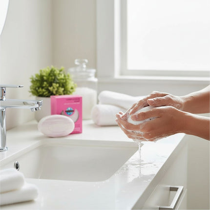 Tia's Treasure Collections Clear Essence Alpha Hydroxy complexion soap being lathered in hands at a bathroom sink.