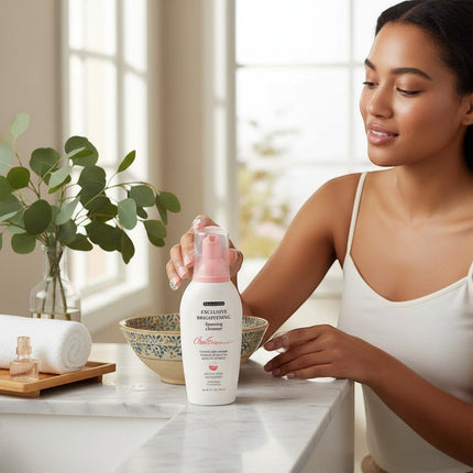 Tia's Treasure Collections Clear Essence brightening foaming cleanser bottle on a marble bathroom vanity with a woman.