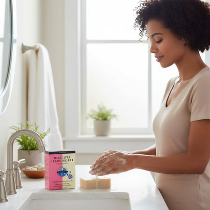 Tia's Treasure Collections medicated cleansing bar with a woman washing her hands in a bright bathroom setting.
