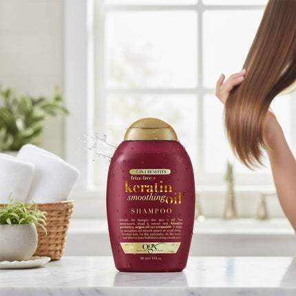 Tia's Treasure Collections OGX Keratin Smoothing Oil 5-in-1 shampoo bottle on a bathroom counter with hair in background