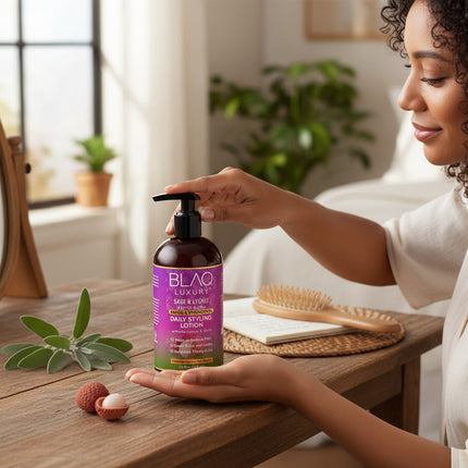 Tia's Treasure Collections Blaq Luxury Sage and Lychee daily styling lotion bottle held by a woman at a wooden table.