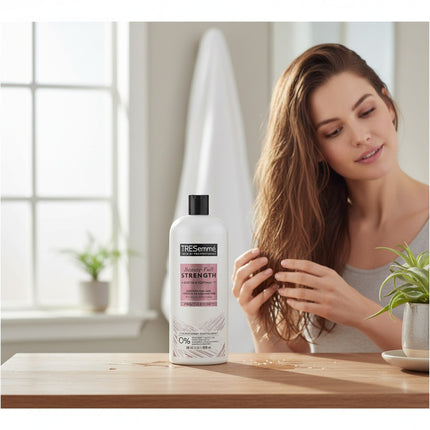 Tia's Treasure Collections Tresemme Beauty-Full Strength Conditioner bottle on a wooden table with a woman