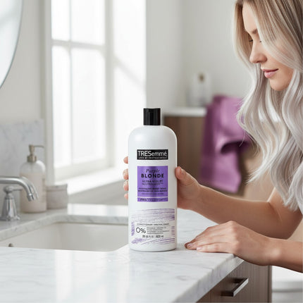 Tia's Treasure Collections Tresemme Purple Blonde conditioner bottle held by a woman with platinum blonde hair.