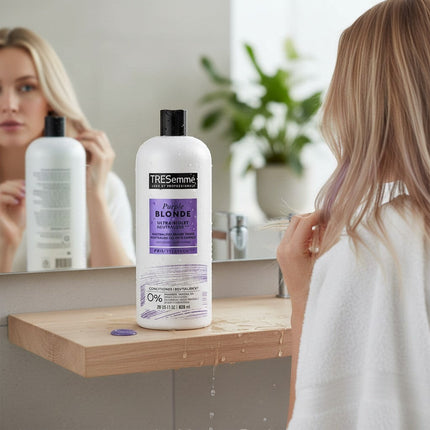 Tia's Treasure Collections Tresemme Purple Blonde conditioner bottle on a bathroom vanity with a woman in the mirror